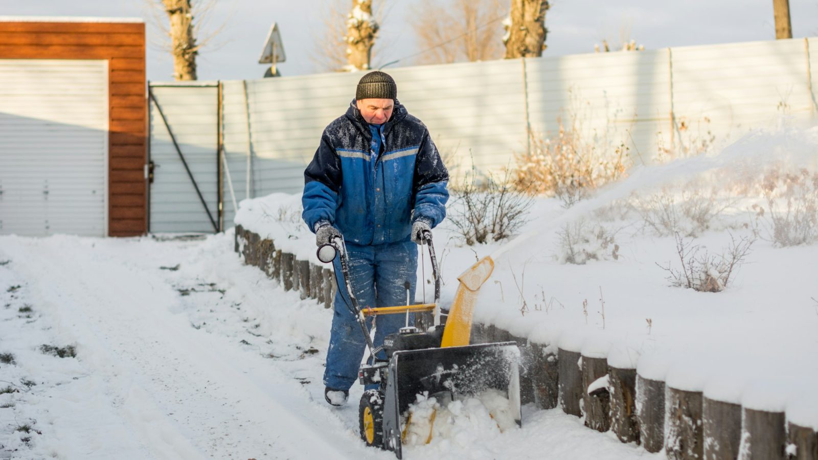A person using a snow blower to clear a driveway
